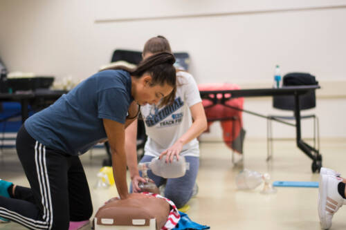 students perform CPR on a dummy